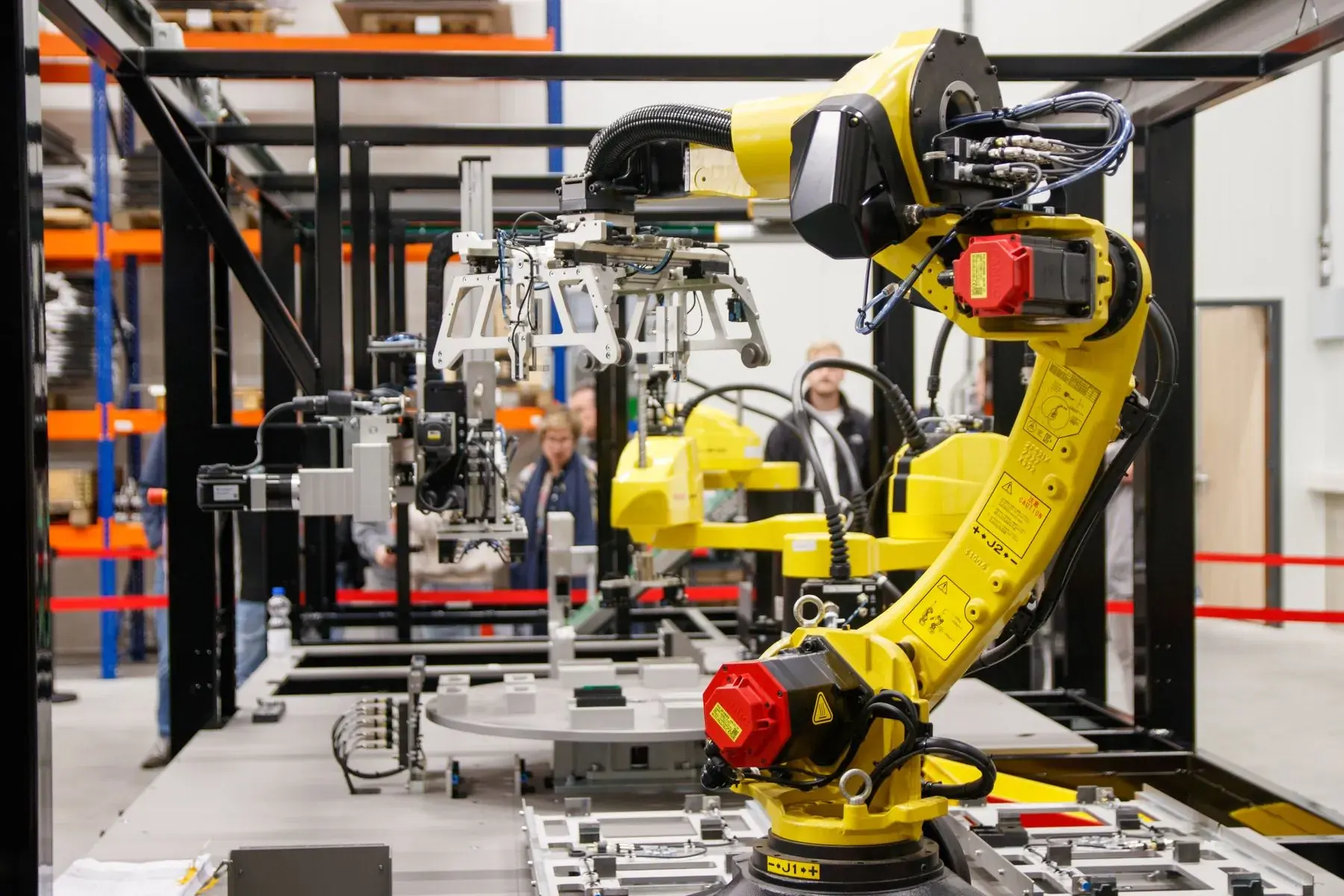A yellow six-axis robot arm inside a guarded work cell, mid-cycle.