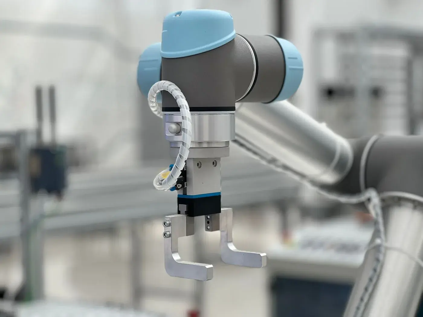 A white collaborative robot arm on a bench in a bright laboratory.