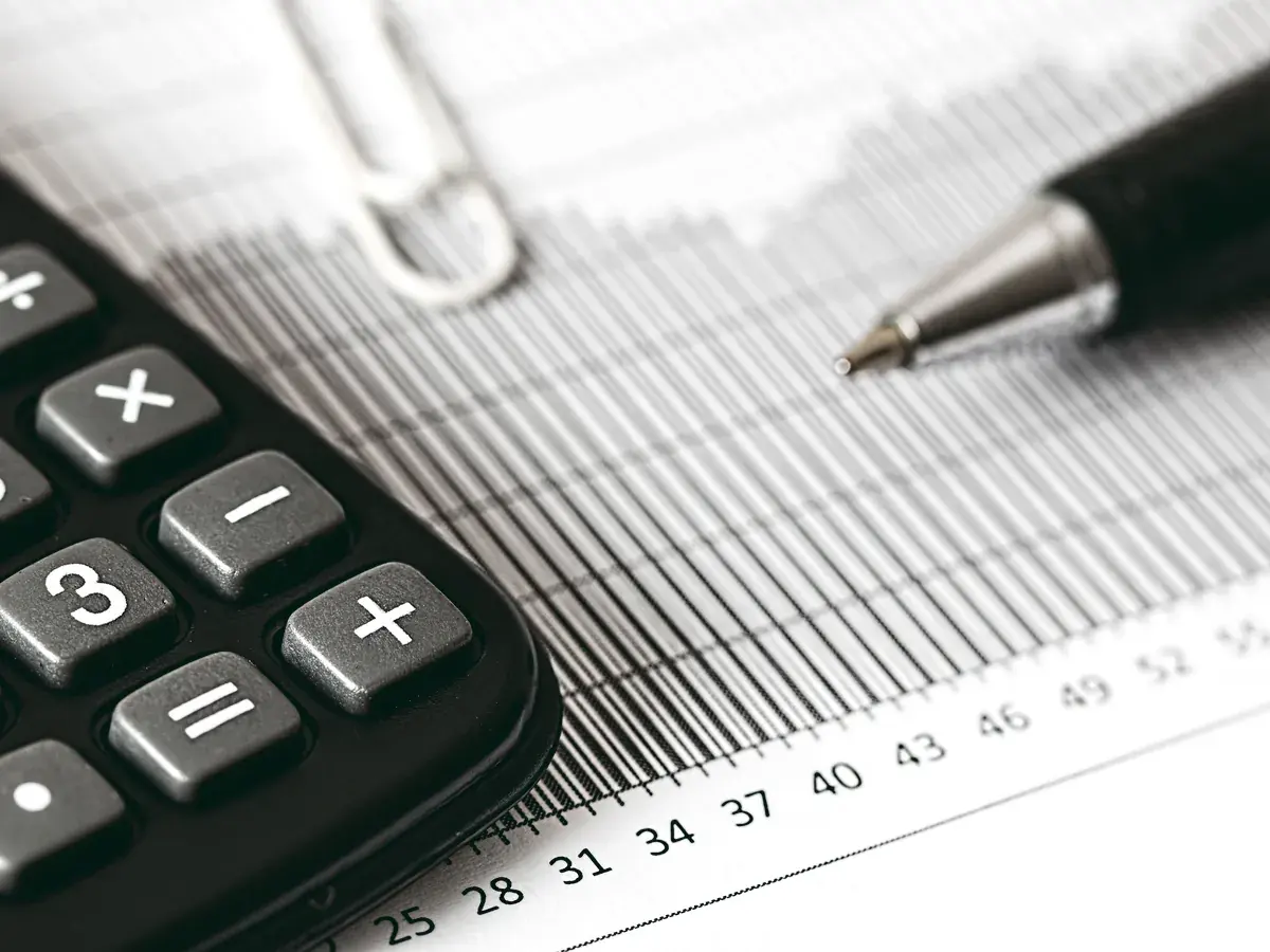 A calculator, a pen and a ruled financial statement on a desk.
