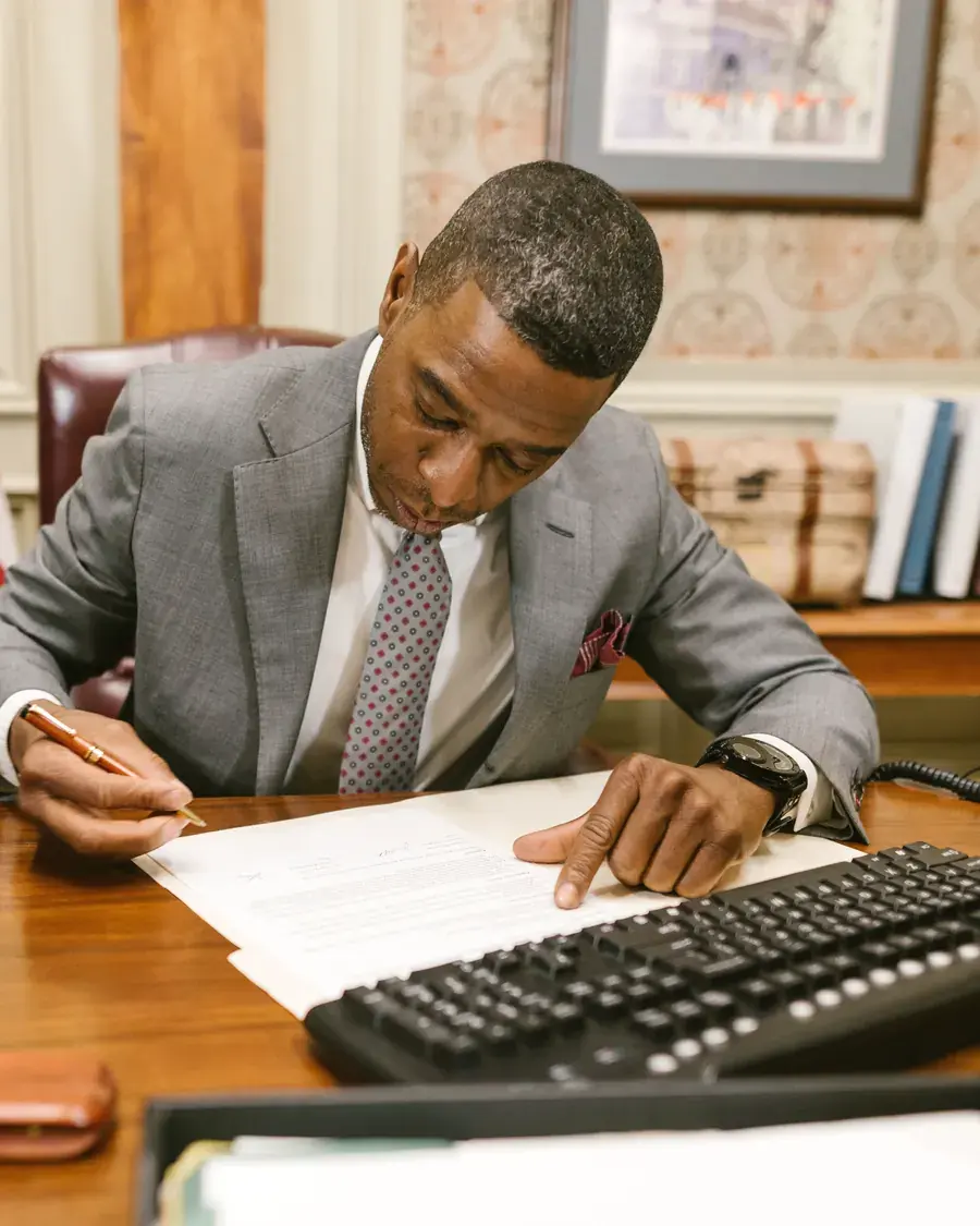 A Morrison & Grey lawyer at his desk, reading through a contract a page at a time.