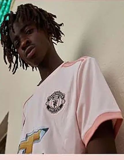 Model with shoulder-length locs, head turned, against a pale wall