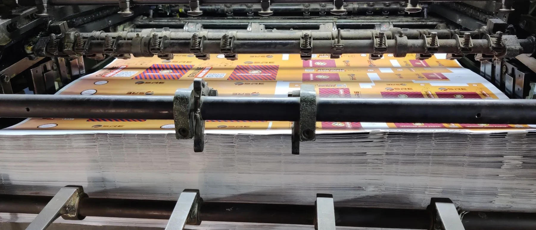 An offset press mid run, four ink ducts open along the bed.