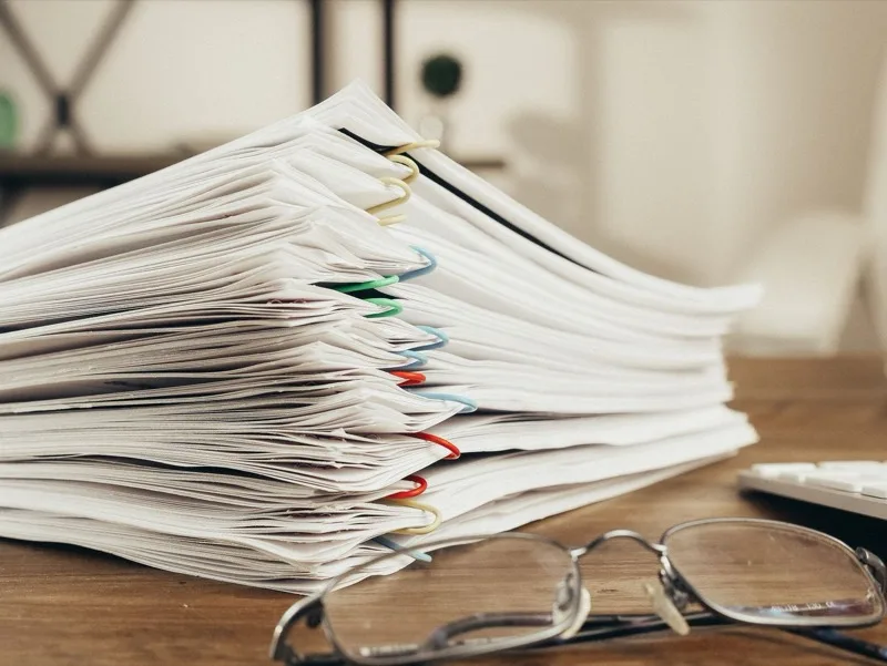 A stack of proof sheets weighted down on a bench.